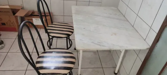 Mesa tampa de mármore com duas cadeiras.